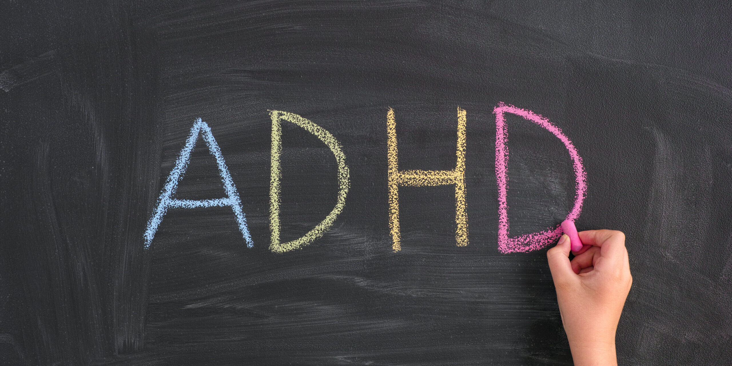 Child writing Abbreviation ADHD on a blackboard