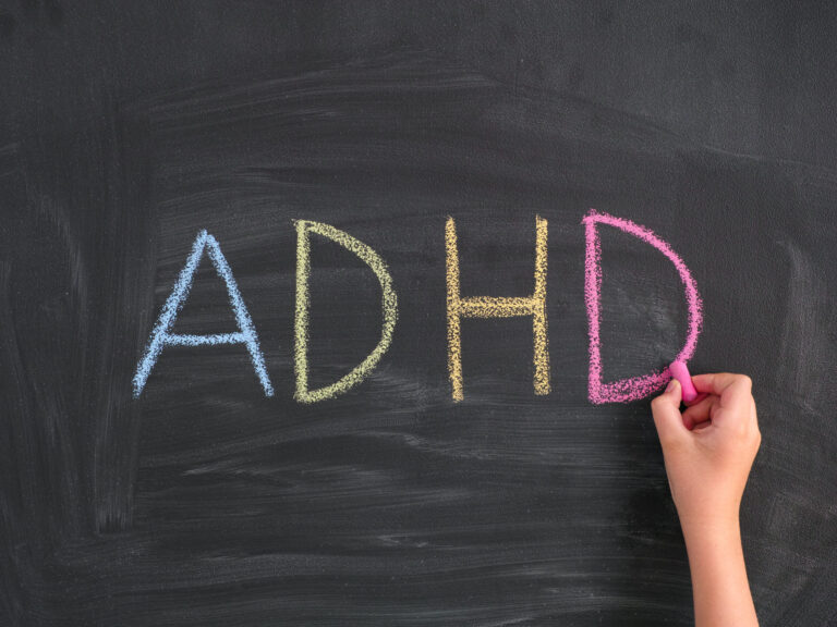 Child writing Abbreviation ADHD on a blackboard